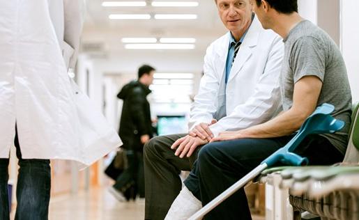 一名拄着拐杖的男子在医院与他的医生交谈